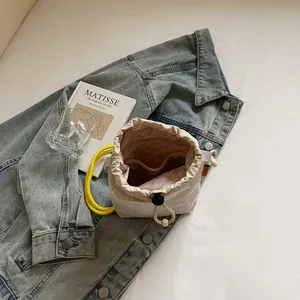 Chic drawstring bucket bag with yellow rope handles on denim background