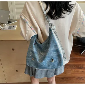 Détail du sac hobo en jean bleu avec papillons argentés et bandoulière en chaîne