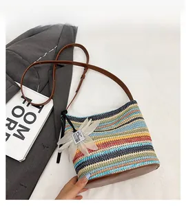 Detailed view of rainbow striped woven bucket bag with leather strap and floral charm