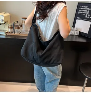 Foto de estilo de vida de un bolso tote de lona negra de gran capacidad llevado por modelo