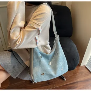 Détail du sac cabas bleu clair avec des papillons argentés sur tissu texturé