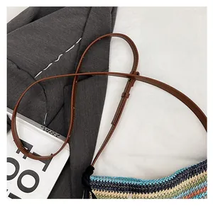 Detail of adjustable brown leather shoulder strap on a colorful woven straw bucket bag