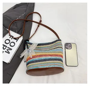 Size comparison of rainbow striped woven straw bucket bag with a mobile phone and flower charm