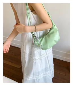 Mint green crescent underarm bag shown on shoulder with elegant white dress outfit