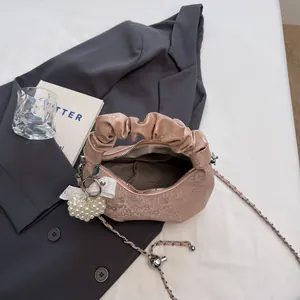 Pleated dumpling handbag in beige embossed leather with chain strap and pearl charm