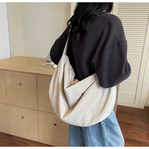 Detailed view of beige large capacity crescent tote bag worn as a shoulder bag