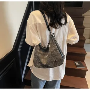 Détail du sac cabas gris à motif papillon avec bandoulière chaîne porté par le modèle