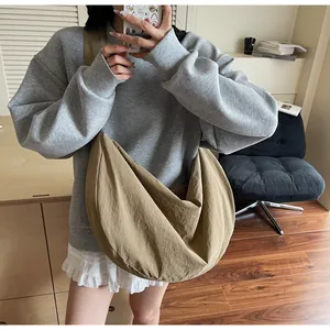 Detail of khaki large woven tote bag with wide shoulder strap worn by a model