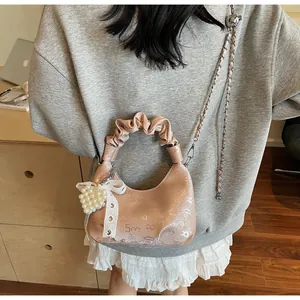 Detail view of pink pleated handbag with silver chain and elegant pearl lace charm
