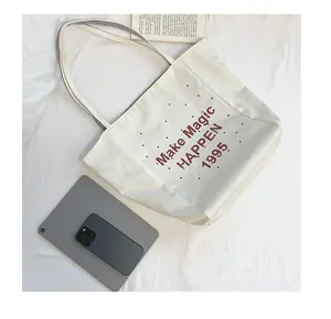 Detail of canvas tote bag with letter print and striped handle showing spacious interior