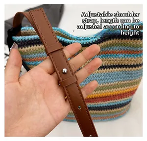 Detail of adjustable leather shoulder strap on a colorful striped woven bucket bag