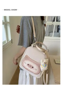 Model view of cream canvas backpack with pink cat print and plush bear pendant detail