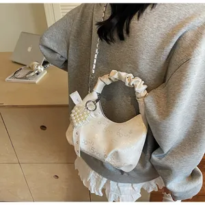 Detail of white pleated handbag with pearl heart charm and lace bow decoration