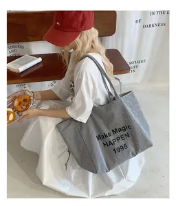 Close-up of striped canvas tote bag with Make Magic HAPPEN 1995 text and red hat accent