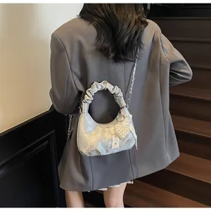 Detail of silver pleated handbag with pearl heart charm and metallic chain strap
