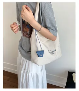 Detail view of large cream canvas tote bag with blue C'est la vie print and mini pouch