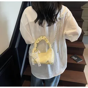 Detail of cream yellow pleated handbag with pearl heart charm and metal chain strap