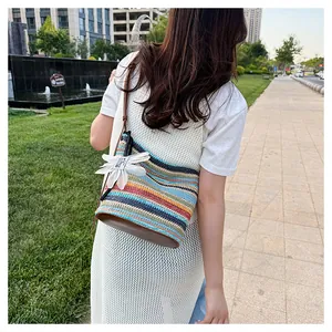 Outdoor view of multi-color rainbow striped straw bucket bag with daisy charm