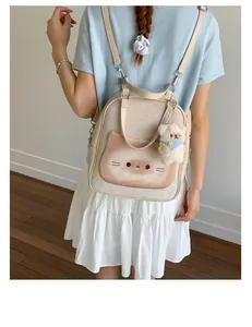 Rear view of model wearing a beige cat-print canvas backpack with bear pendant and leather straps