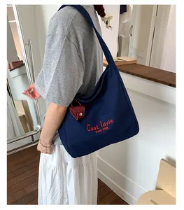 Close-up of a navy canvas tote bag featuring red embroidery and a red leather charm