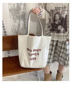 Detail of canvas tote bag with red lettering, black dots and striped shoulder strap