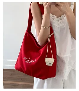 Detail of red canvas tote bag with C'est la vie text and mini cream pouch accessory