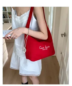 Detail of red canvas tote bag with white lettering and mini pouch on wide strap