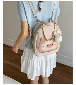 Detail view of beige backpack with cat pattern and plush bear charm on back