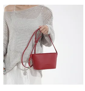 Detail of red bucket bag featuring pebble leather texture and silver heart charm pendant