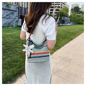 Detail of colorful rainbow striped crochet bucket bag with leather strap and flower charm