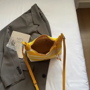 Sac hobo rayé en maille avec bordure en cuir jaune et bandoulière sur un blazer gris