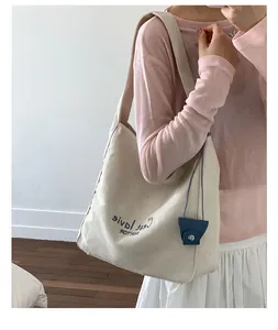 Detail of canvas tote bag with C'est la vie print and small blue decorative pouch