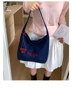 Close-up of Navy Canvas Hobo Bag with red embroidery C'est La Vie and leather charm