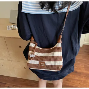 Détail d'un sac bandoulière en maille rayée avec logo en cuir et pendentif en corde tressée