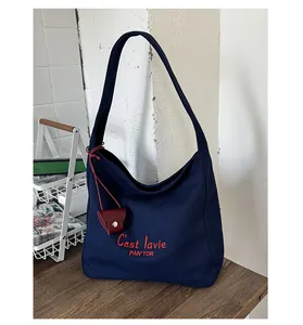Detail of navy canvas tote featuring red embroidery and leather coin purse accessory