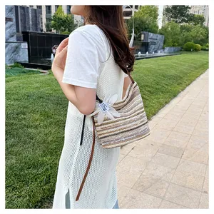 Detail of a rainbow striped woven bucket bag featuring a large white flower pendant