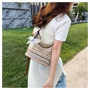 Detail of striped woven bucket bag with leather strap and white flower charm outdoors