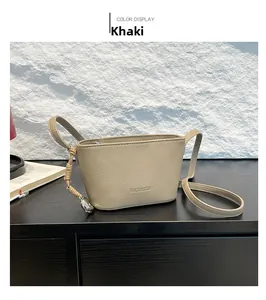 Detail of khaki bucket bag showing litchi texture and braided strap with metal charm