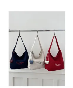 Detailed shot of three minimalist canvas tote bags in blue, cream and red on a metal rack