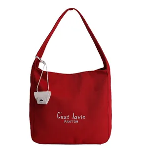 Large red canvas tote bag with white embroidery and a small cream hanging pouch