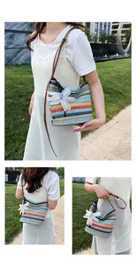 Close-up of rainbow striped straw bucket bag featuring a large white fabric flower charm