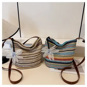 Close-up of rainbow striped straw woven bucket bags with elegant white organza flower pendant