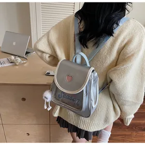 Detail of silver blue mini backpack with heart cutout and fluffy white charm on a model