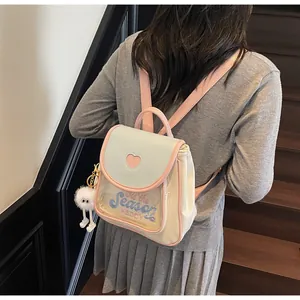 Detail of cute pastel mini backpack with heart-shaped window and plush charm on wooden stairs