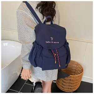 Detalle de mochila de lona azul marino con bordado rosa y cierre de cordón ajustable