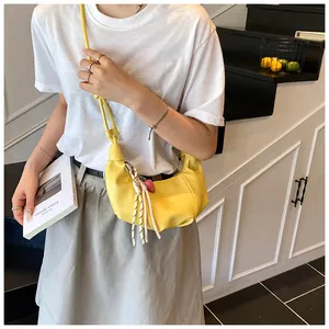 Détail du sac croissant jaune avec design plissé sur le côté et gland en corde coloré