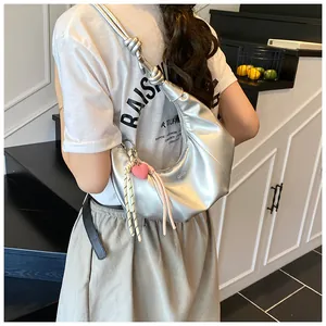 Détail du sac hobo argenté avec bandoulière nouée et pendentif cœur rose