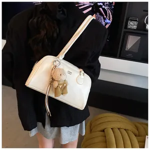 Détail du sac à bandoulière en cuir blanc brillant avec charmant ours en peluche