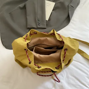 Mochila tipo cubo de lona amarillo jengibre con cordón trenzado y bolsillos interiores