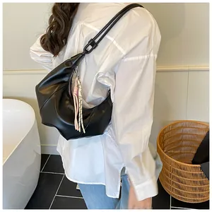 Détail d'un sac demi-lune noir avec pompon à nœuds et design plissé pour femme